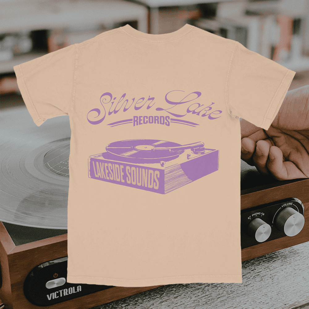 A merch mockup of a peach tee over a record player, printed Silver Lake RECORDS in lilac script above a turntable labelled LAKESIDE SOUNDS.
