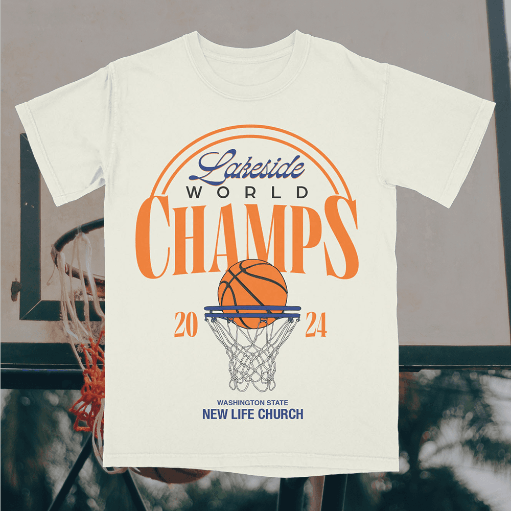 A merch mockup of a cream tee over a basketball hoop, printed Lakeside WORLD CHAMPS in orange serif with a ball in a net and WASHINGTON STATE NEW LIFE CHURCH.