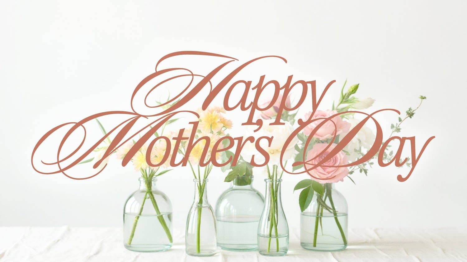 A soft white Mother's Day slide with Happy Mother's Day in flowing rust calligraphy across a photo of pink and cream blooms in glass bud vases.